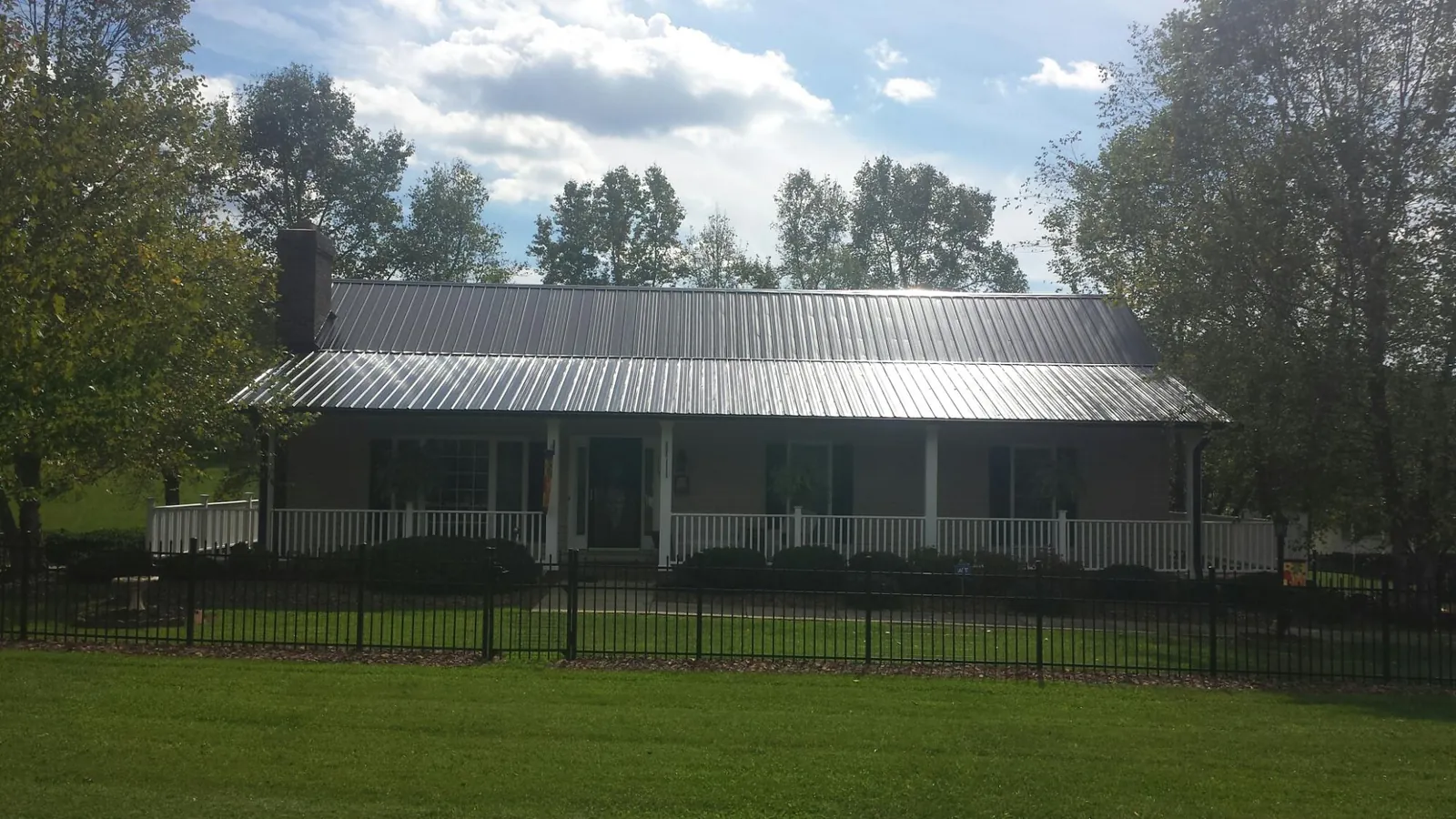 Gray metal roof on a brick ranch with a full width front porch — Gutter Guard Installation work by our crew in Versailles