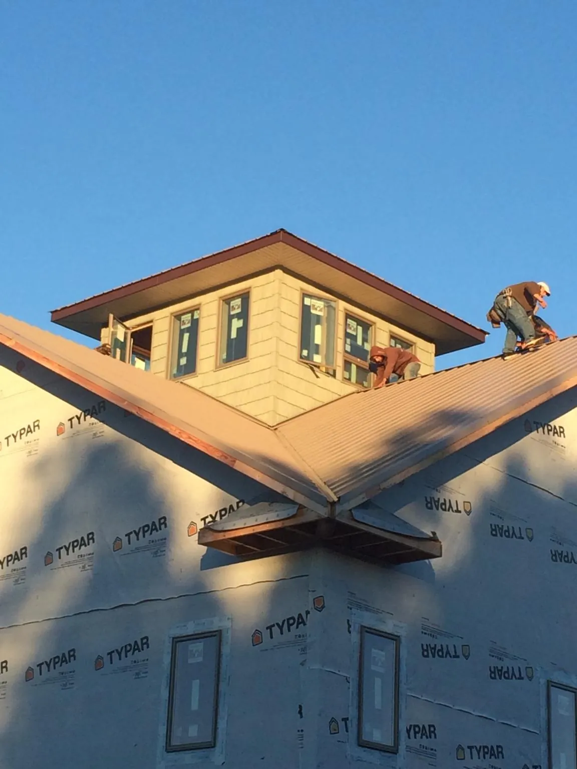 Roofers working around a rooftop cupola on a new metal roof at sunset — Roof Waterproofing in Versailles by Roofing Brothers